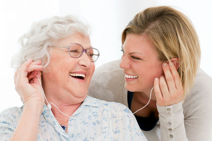 Senior woman enjoying music with staff member