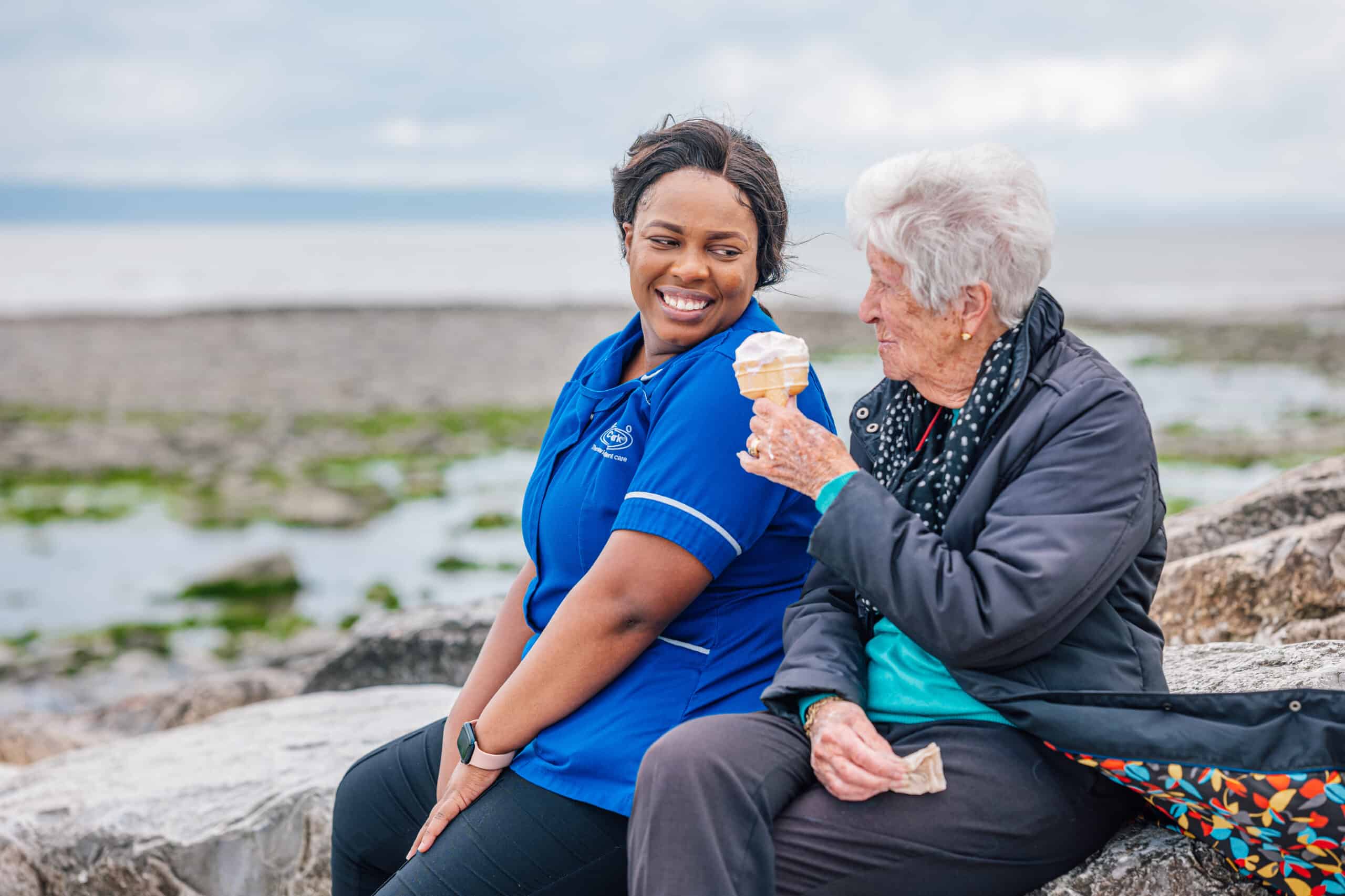 Staff member and resident enjoying ice cream outdoors.