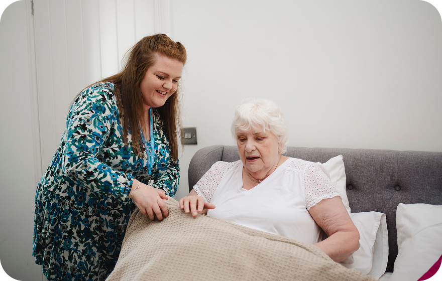 Staff assisting a senior resident in a cozy indoor setting.