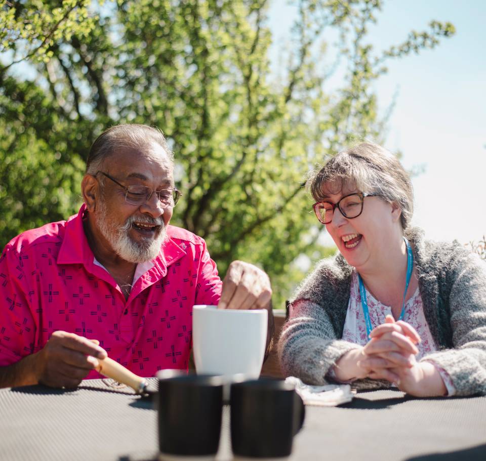 Two seniors enjoying coffee outdoors.