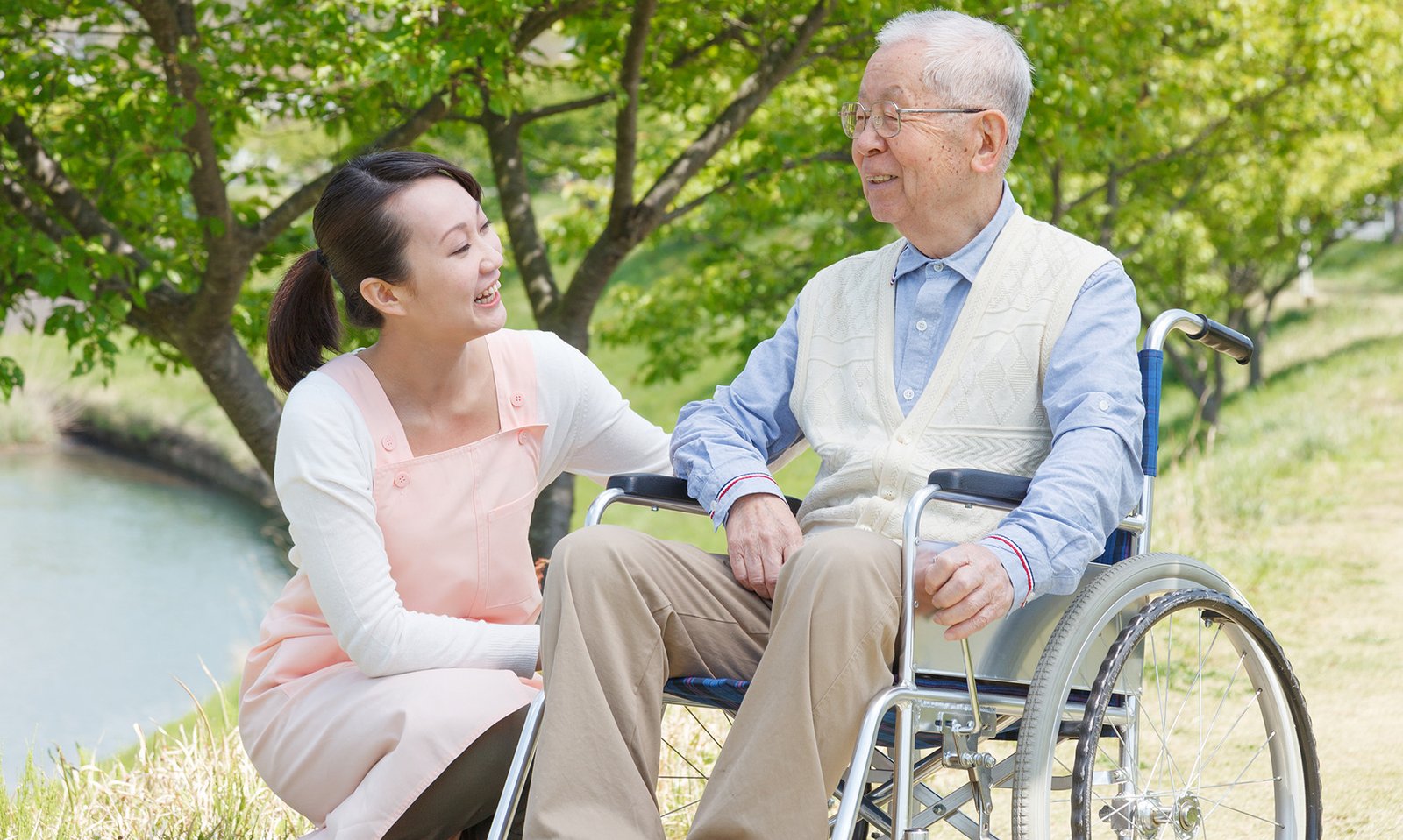 Caregiver interacting with elderly resident outdoors.