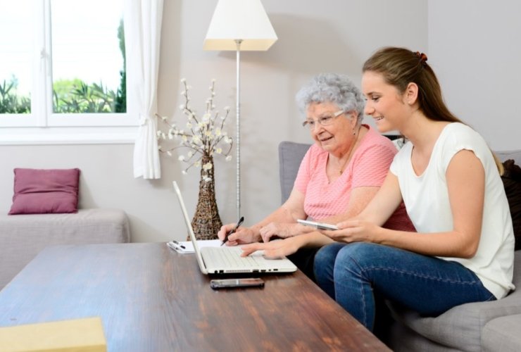 Senior resident and caregiver using a laptop together.