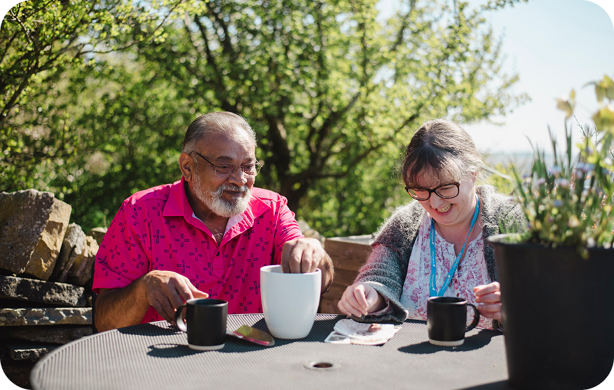 Two residents enjoying coffee outdoors in the sun.