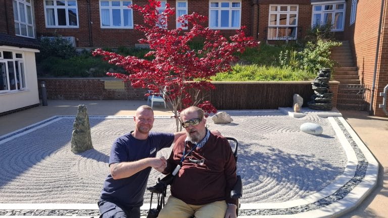 Resident and staff member in a landscaped garden