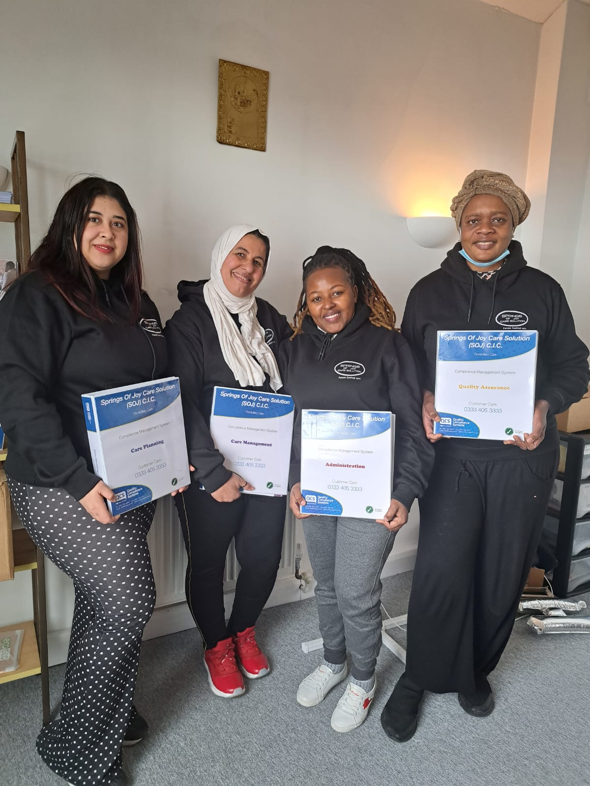 Staff members holding certificates in an interior space.
