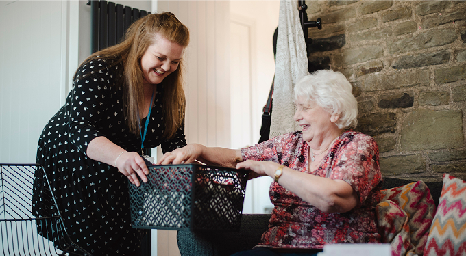 Staff member assisting a senior resident indoors.