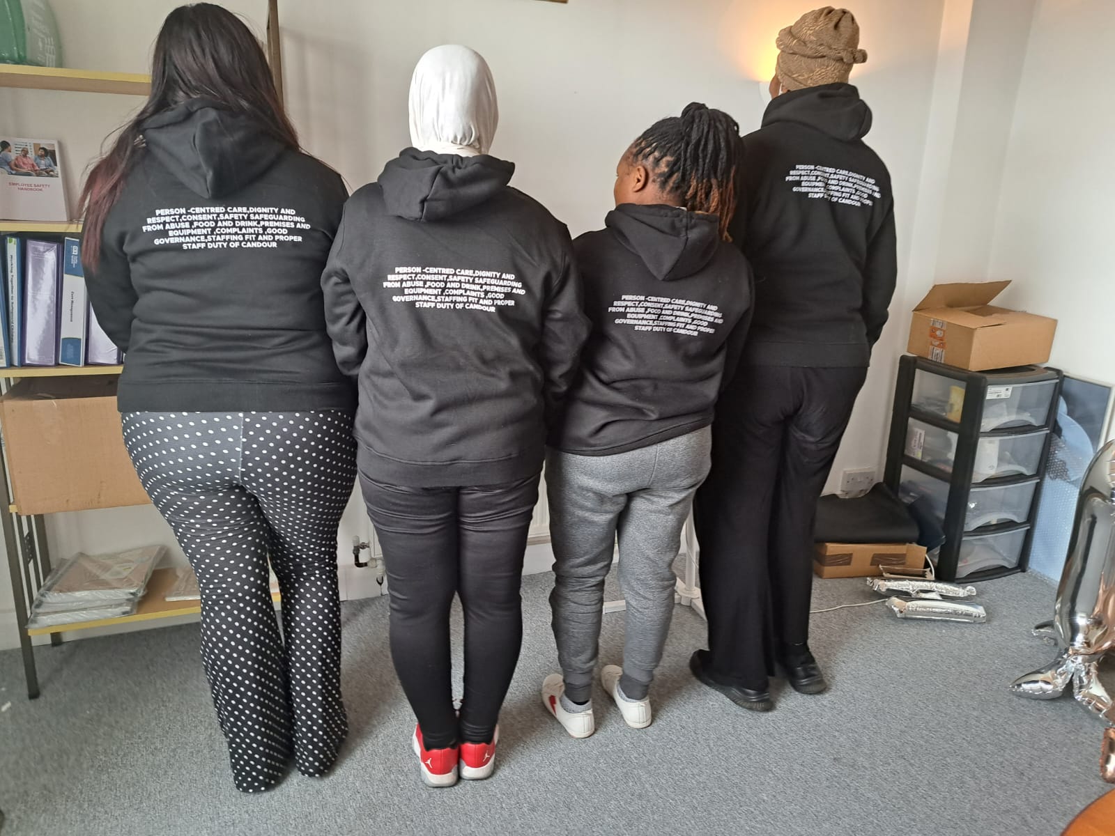 Staff members wearing matching hoodies in an office setting.