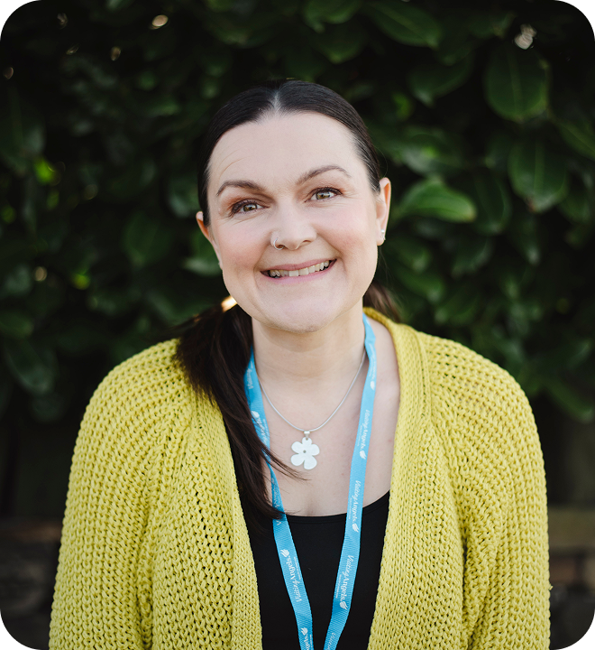 Staff member smiling in front of greenery