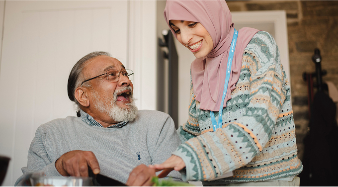 Senior man enjoying interaction with female caregiver.