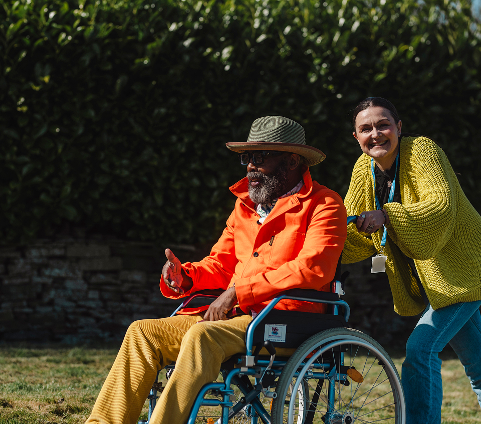 Resident in wheelchair with caregiver outdoors