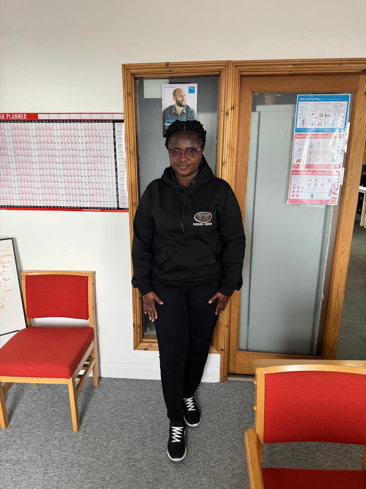 Staff member in a black hoodie standing in an office area
