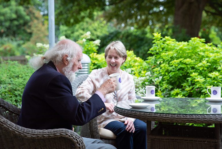 Residents enjoying tea in a garden setting.