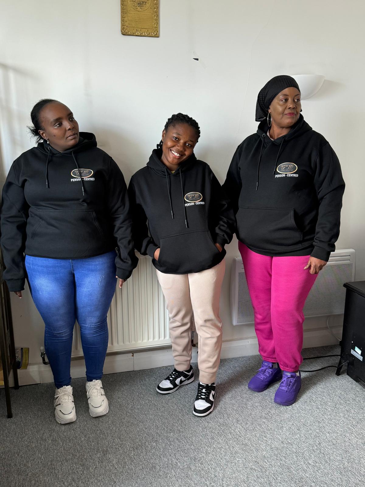 Three staff members wearing branded hoodies.