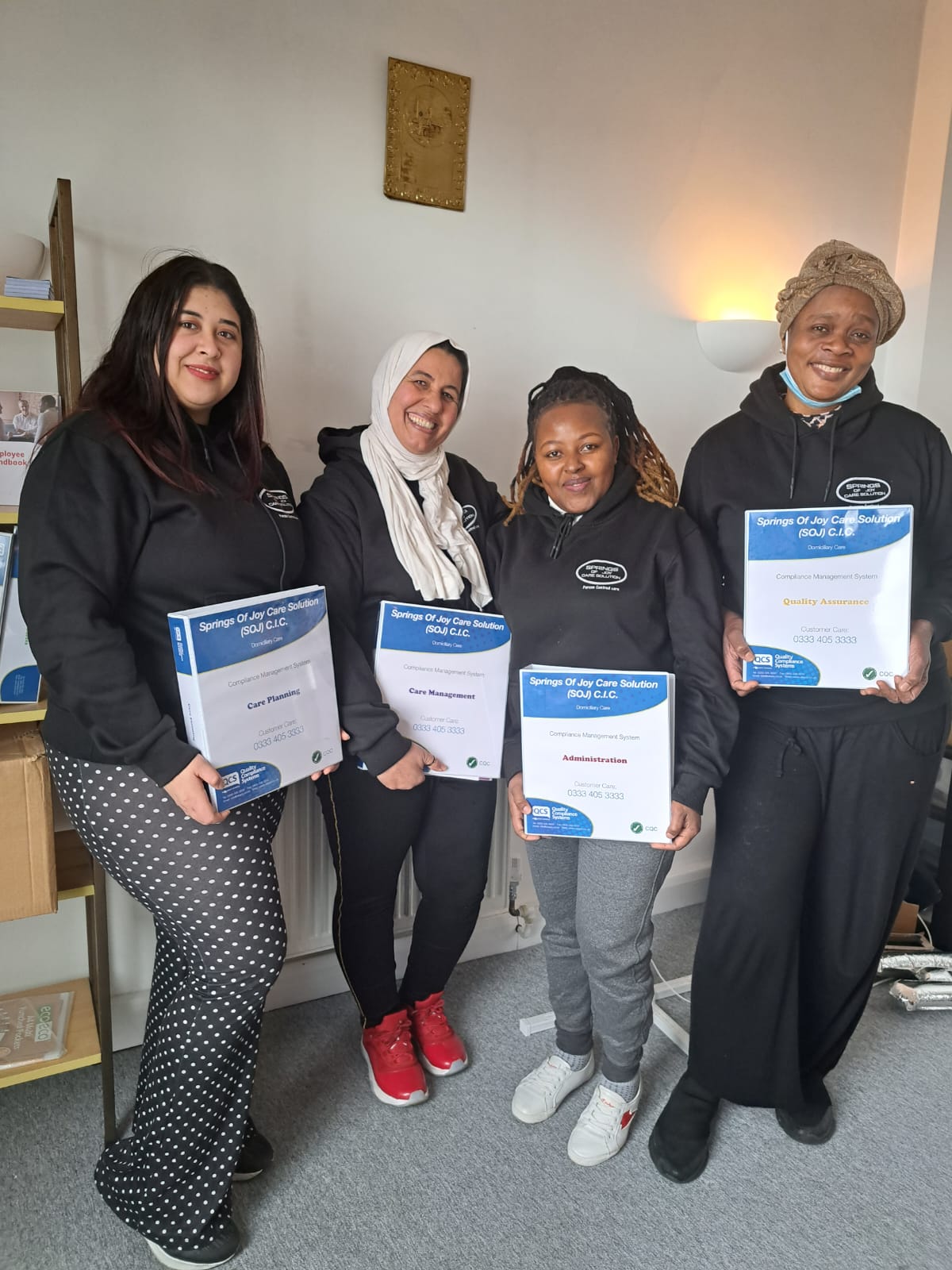 Staff members holding certificates and smiling.