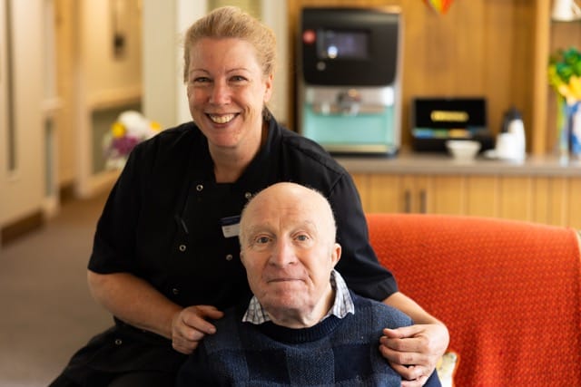 Staff member smiling with resident in a common area