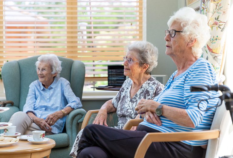 Three elderly women enjoying each other's company indoors.