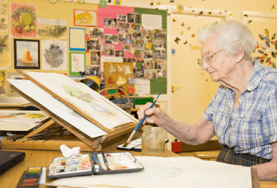 Elderly woman painting in an art class