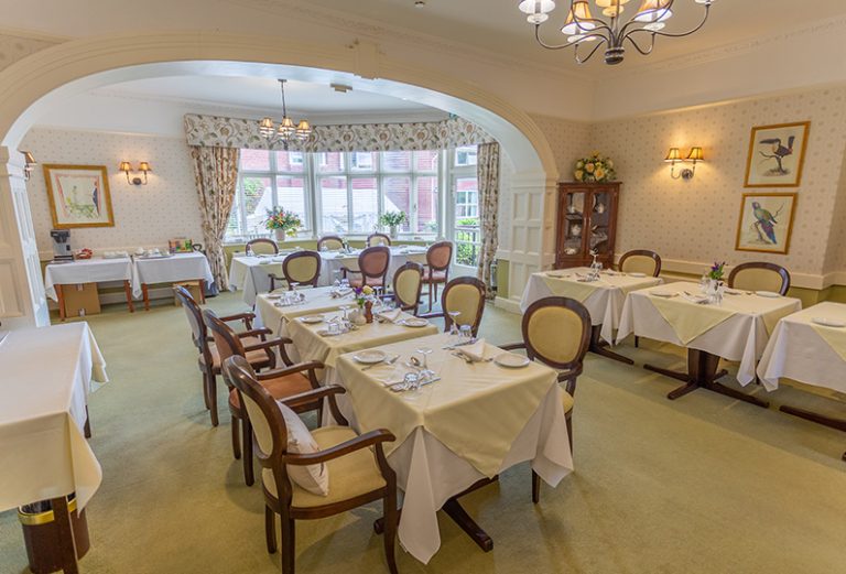 Dining room with neatly set tables and floral decor.