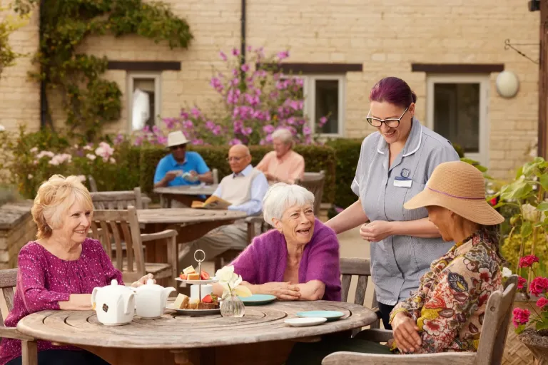 Residents and staff interacting outdoors at a care home.