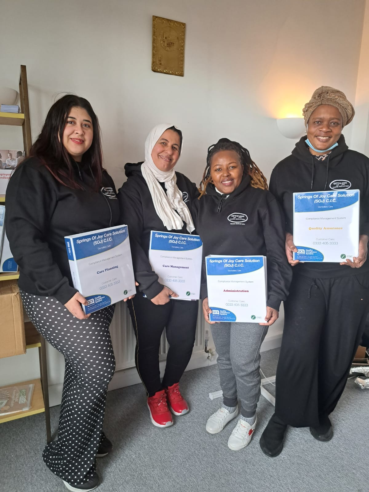 Staff members holding certificates in a common area.