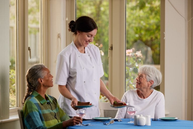 Staff serving food to residents in dining area