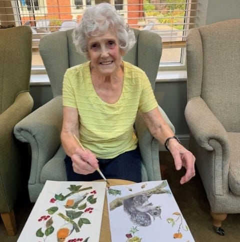 Senior woman painting at a table in a common area