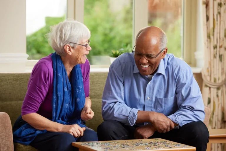 Two seniors enjoying a puzzle together indoors.