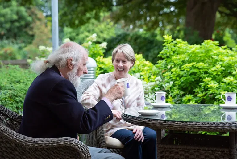 Resident enjoying tea with staff in garden