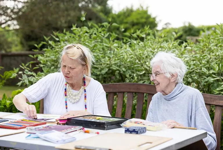 Two women engaged in an outdoor art activity.