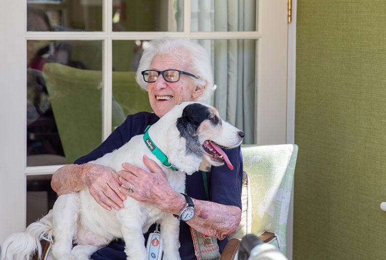 Senior woman joyfully holding a dog indoors