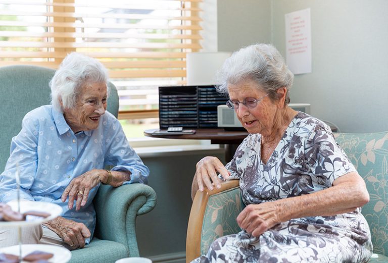 Two elderly women chatting in a cozy room.