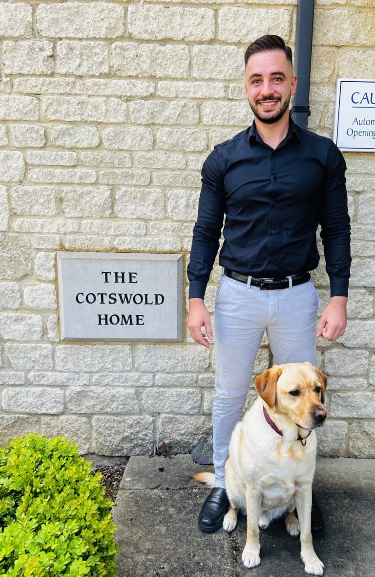 Smiling staff member with a dog outside facility