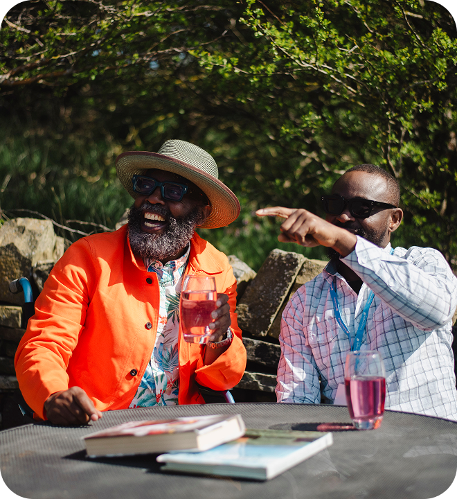 Two men enjoying drinks outdoors in a garden setting.