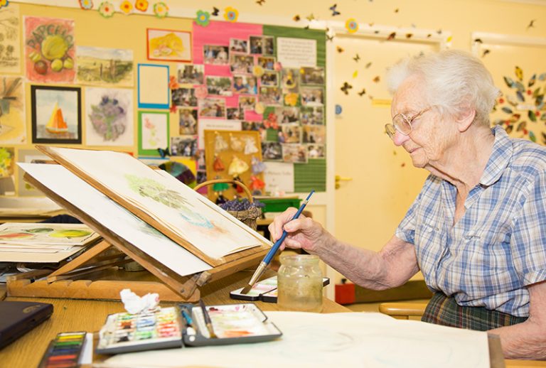 Elderly woman painting in a common area