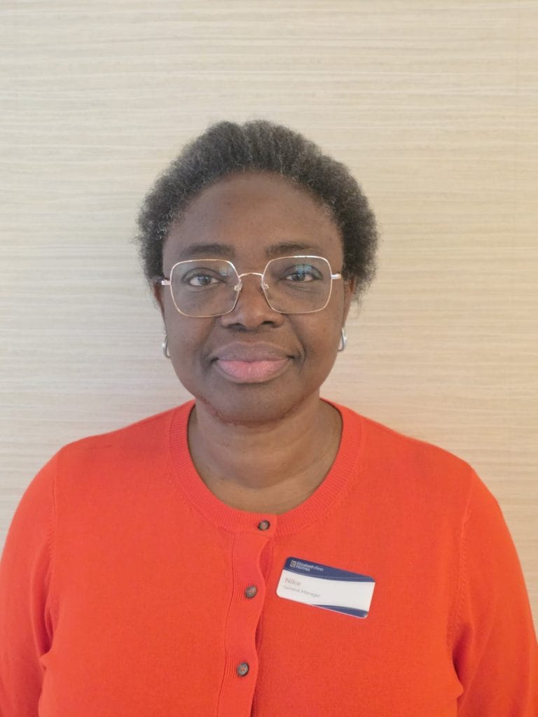 Staff member in orange sweater with name badge