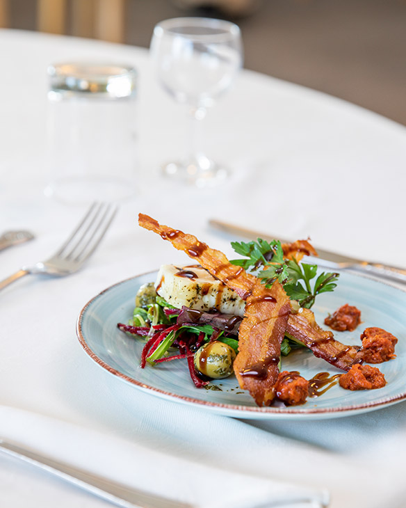 A plated meal with vegetables and bacon strips.
