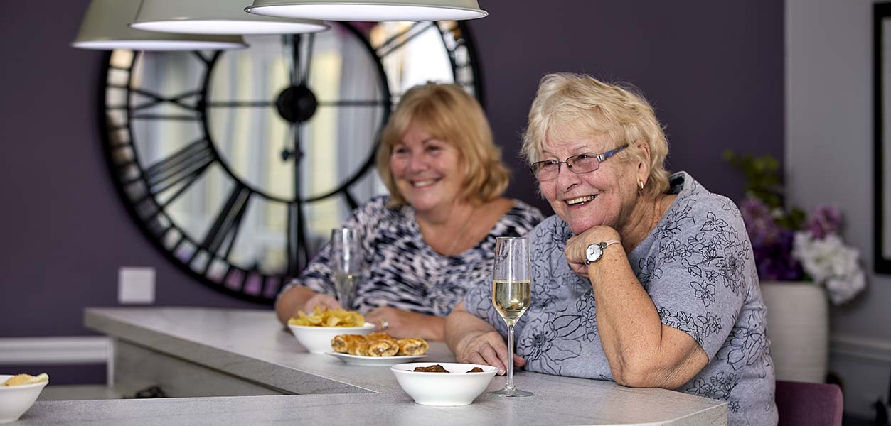 Two women enjoying snacks and drinks at a bar