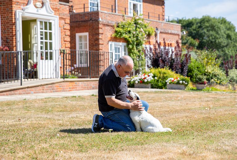 Resident enjoying time with a dog on the lawn