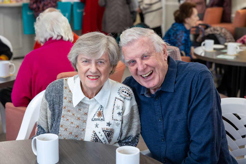Happy seniors enjoying coffee together in a common area.