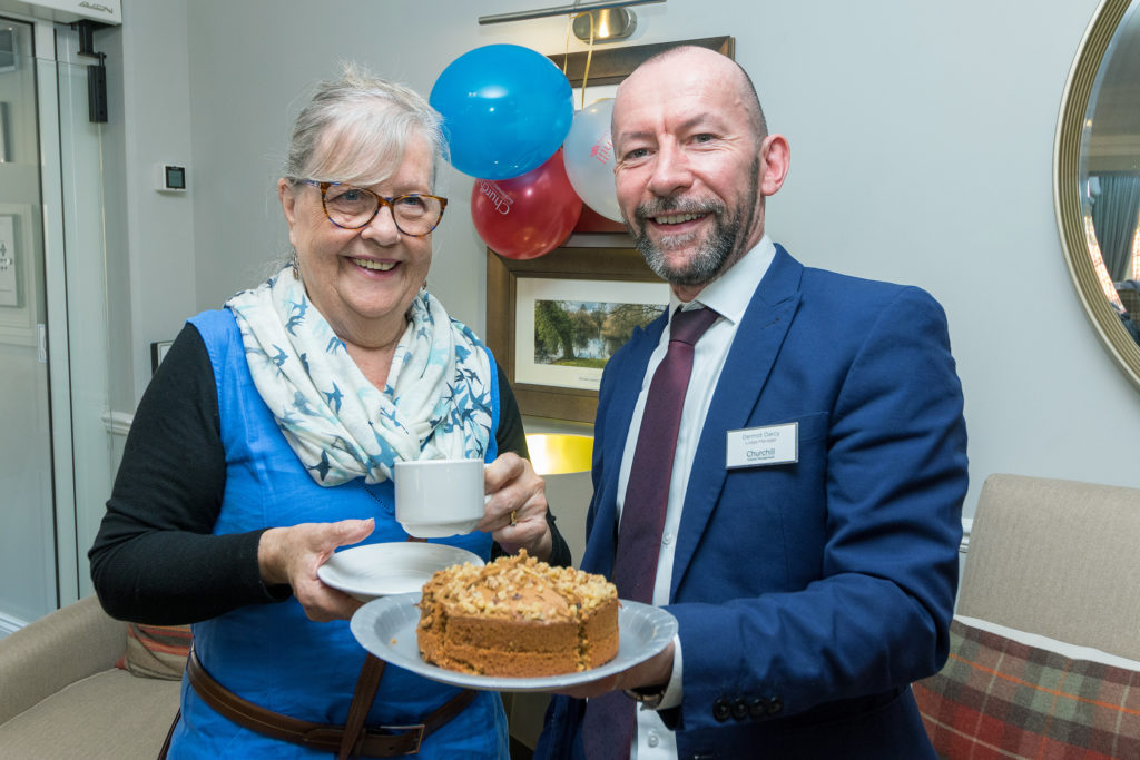 Celebration with resident and staff member holding cake.