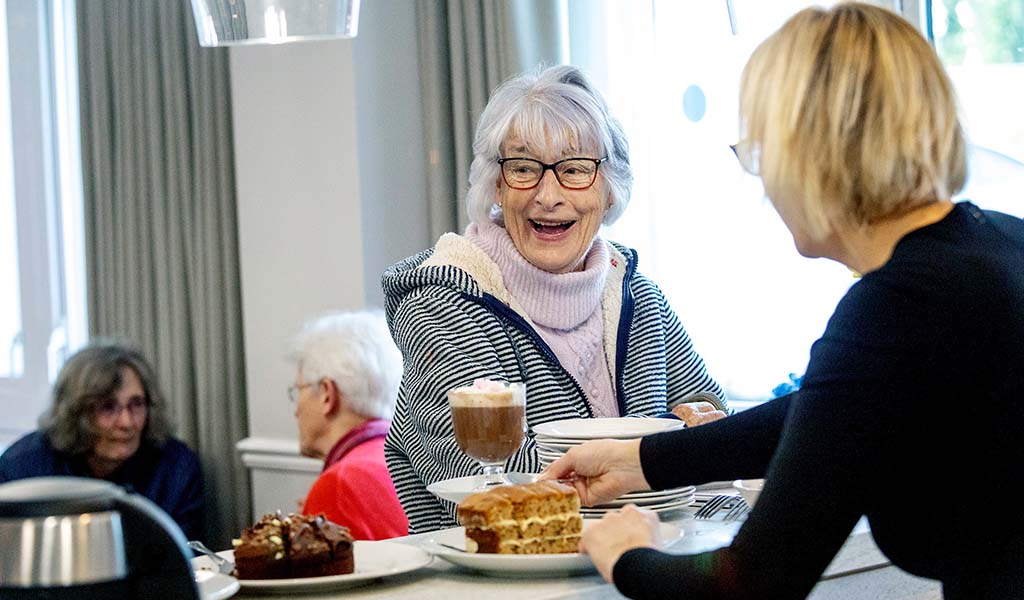 Resident enjoying food with staff assistance.
