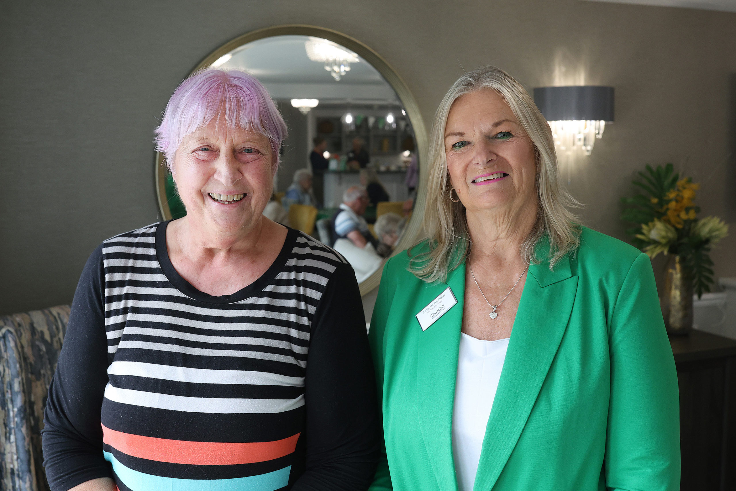 Two women smiling in a common area.