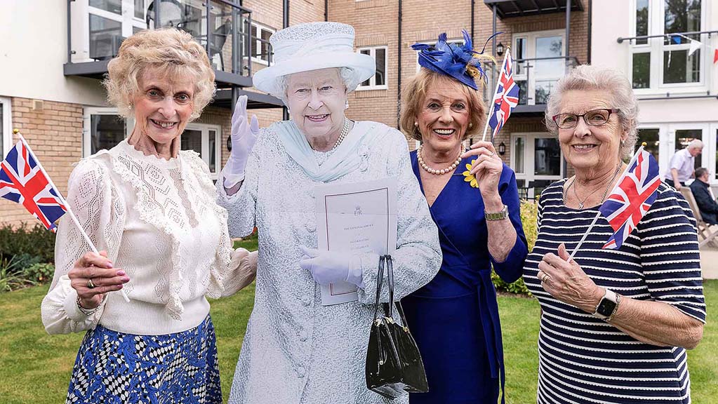 Residents celebrating with a cutout of a royal figure outdoors.
