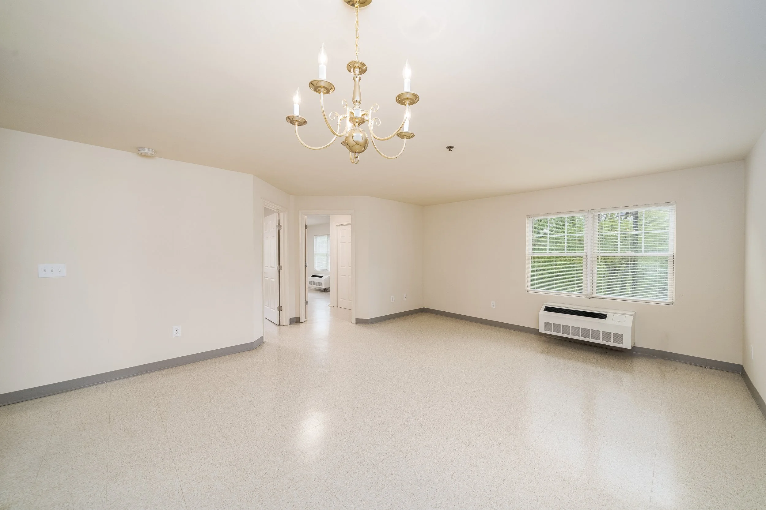 Empty common area with a chandelier and window.