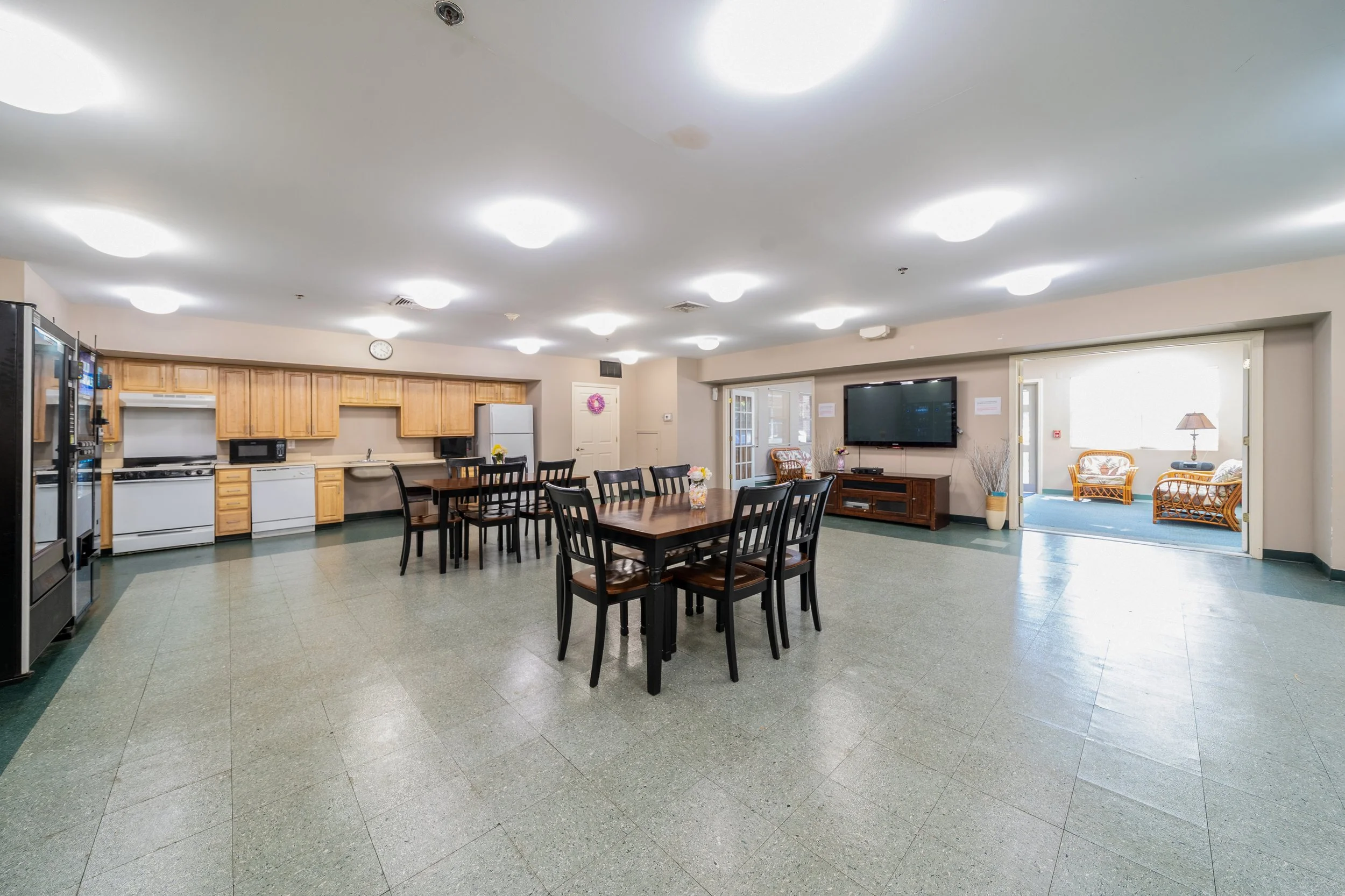 Spacious common area with dining tables and kitchen access.