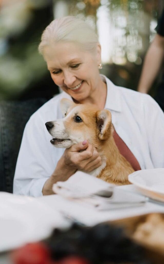 A resident smiling while holding a dog in a cozy setting