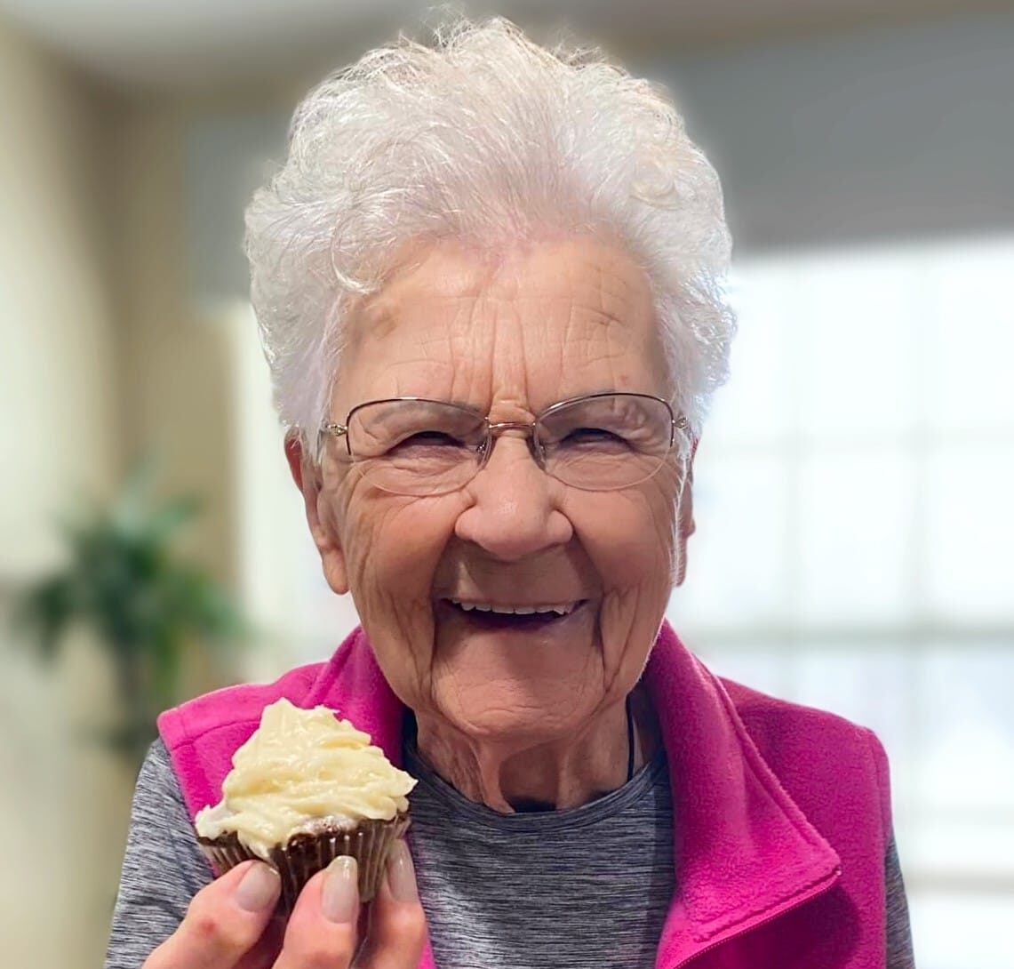Resident happily holding a cupcake indoors
