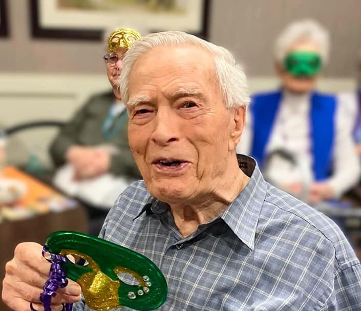 Senior man smiling and holding a mask during a celebration