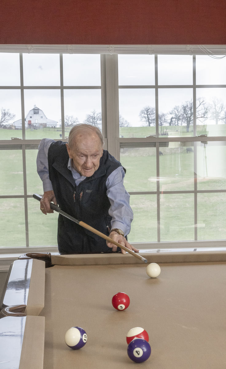Senior resident playing billiards in a well-lit room