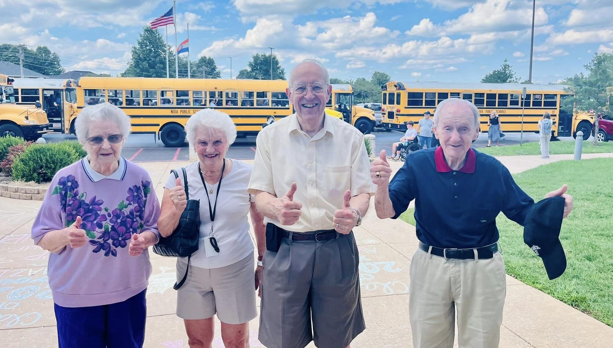 Residents enjoying a sunny day outdoors with school buses in background